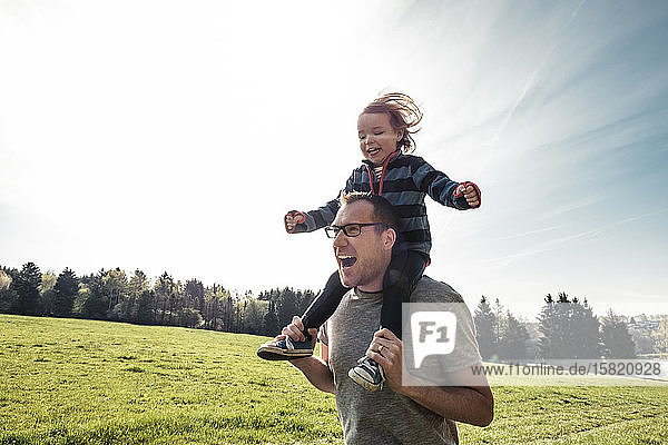 Portrait of father carrying little daughter on his shoulders