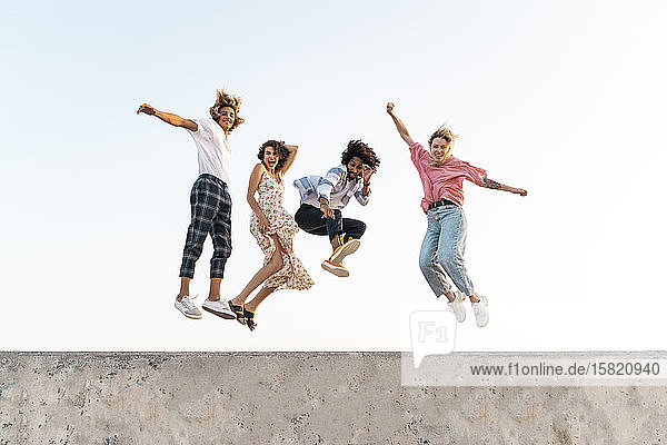 Carefree friends jumping on a concrete wall
