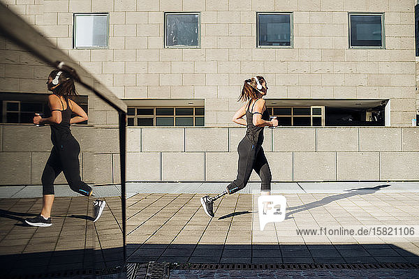 Sportliche junge Frau mit Beinprothese läuft in der Stadt