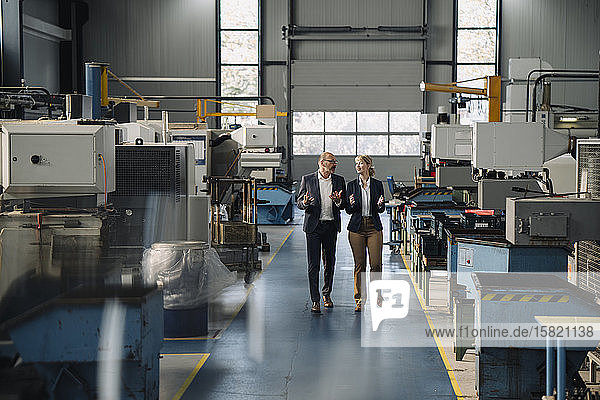 Businessman and businesswoman walking and talking in a factory