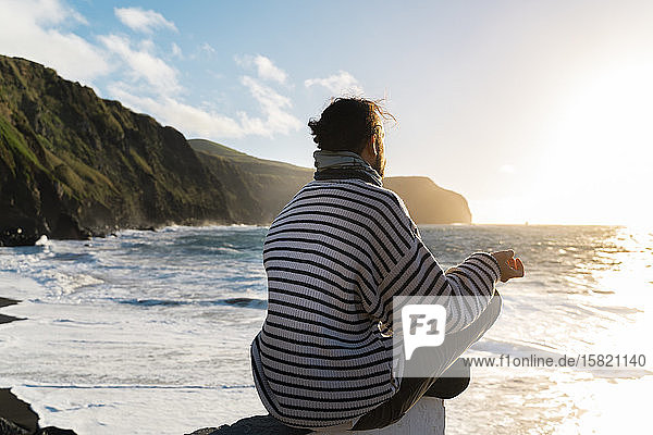 Mann meditiert bei Sonnenuntergang an der Küste  Sao-Miguel-Insel  Azoren  Portugal