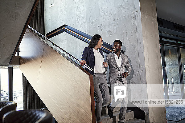 Businessman and businesswoman walking down staircase