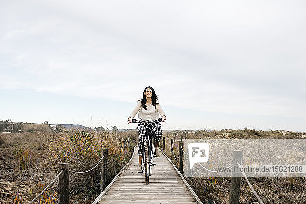 Fahrradfahrende Frau auf einer Strandpromenade auf dem Land