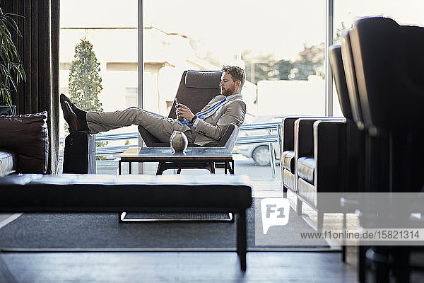 Businessman using smartphone in hotel lobby