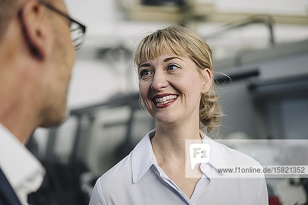 Happy woman looking at businessman in a factory