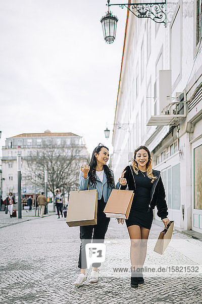 Zwei junge Frauen gehen mit Einkaufstaschen auf der Straße  Lissabon  Portugal