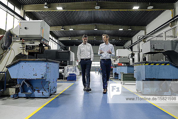 Two men walking and talking in a factory
