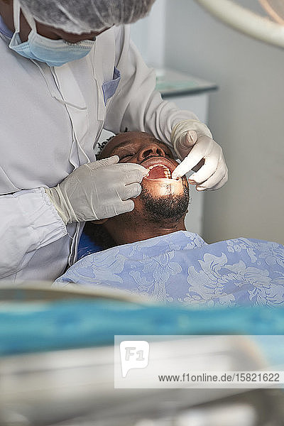 Zahnärztin untersucht Zähne eines Mannes