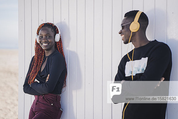 Porträt einer glücklichen Teenagerin und eines jungen Mannes mit Kopfhörern im Freien