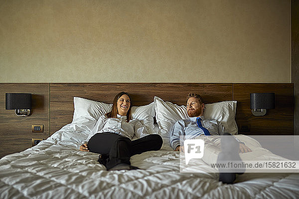 Geschäftsmann und Geschäftsfrau liegen auf dem Bett im Hotelzimmer