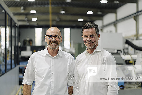 Porträt von zwei lächelnden Geschäftsleuten in einer Fabrik