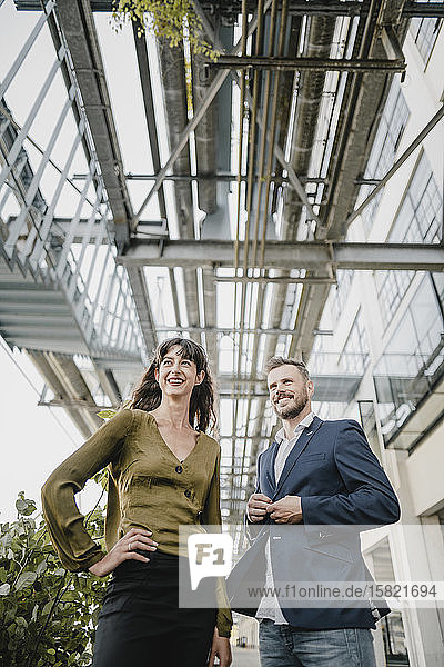 Smiling businessman and casual businesswoman standing outdoors
