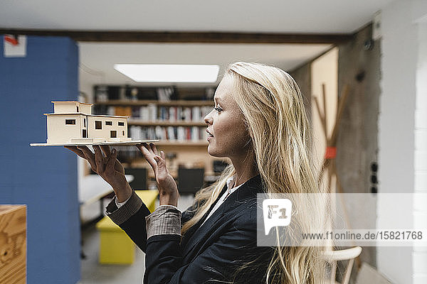 Junge Geschäftsfrau im Loft-Büro mit Architekturmodell