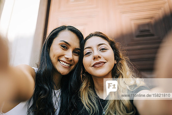 Portrait of two happy friends taking selfie
