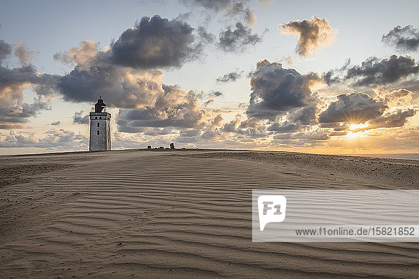 Denmark  Lonstrup  Clouds over rippled sand dunes and Rubjerg Knude Lighthouse at sunset