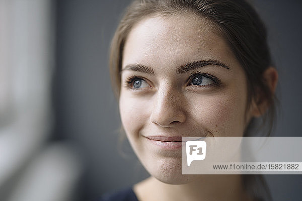Porträt einer lächelnden jungen Frau  die in die Ferne schaut