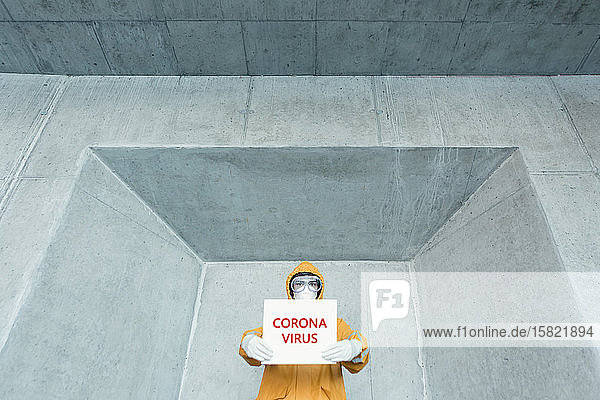 Porträt eines Mannes in Schutzkleidung mit Corona-Virus -Schild