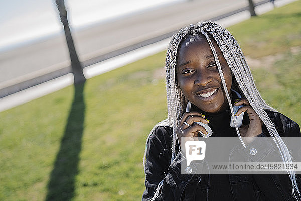 Porträt einer lächelnden Teenagerin mit Zöpfen im Freien
