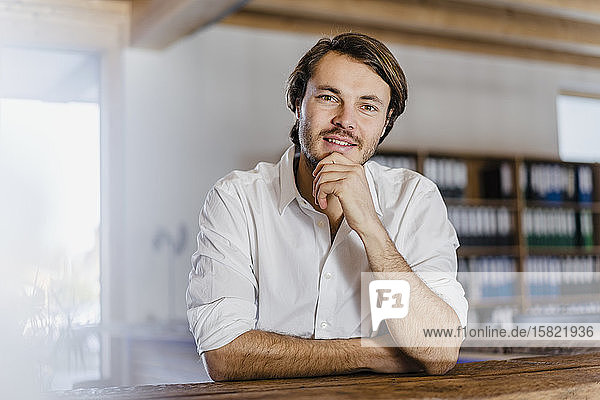 Porträt eines selbstbewussten Geschäftsmannes im hölzernen Großraumbüro