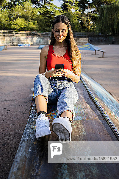 Junge Frau benutzt Smartphone im Skatepark