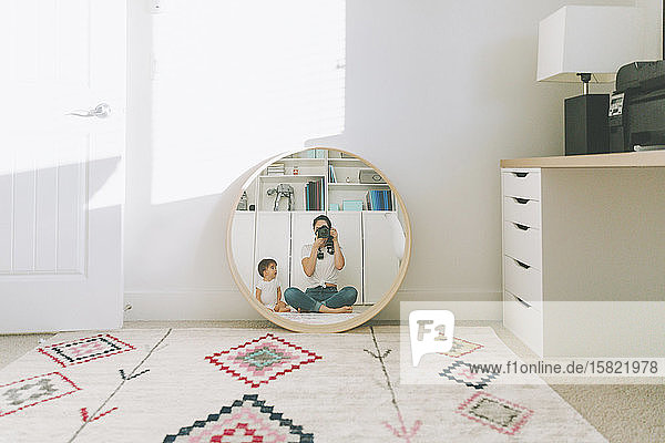 Reflection of mother taking a photograph of herself and baby in the mirror