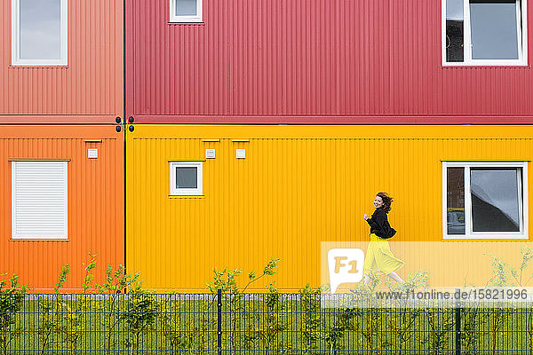 Frau rennt vor einem bunten zweistöckigen Containergebäude