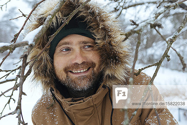 Portrait of smiling man wearing hooded jacket in winter