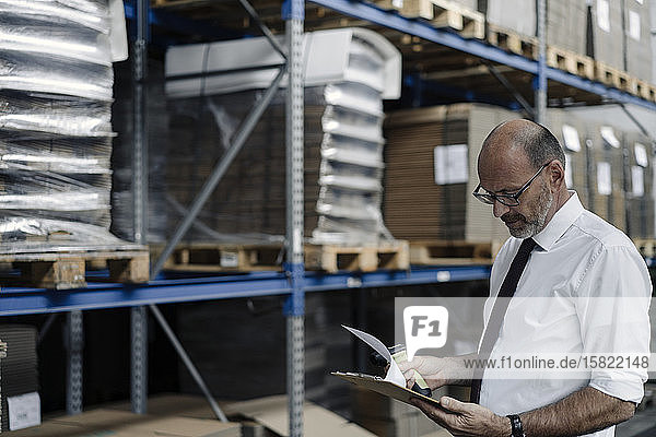 Man with clipboard and scanner in factory warehouse