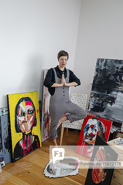 Porträt einer Malerin in Yoga-Pose in ihrem Atelier