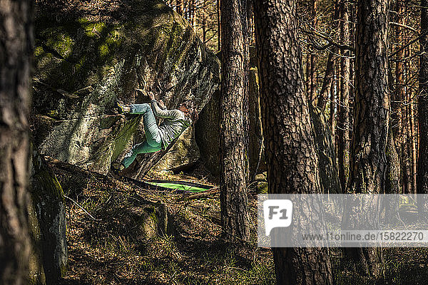 Female climber bouldering on rock in forest  Hochberg  Edenkoben  Rhineland-Palatinate  Germany
