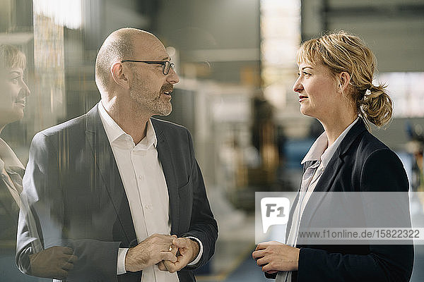 Geschäftsmann und Geschäftsfrau im Gespräch in einer Fabrik
