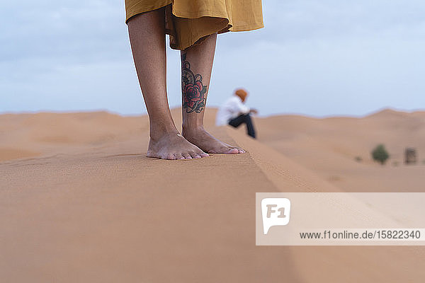 Füße einer auf einer Sanddüne in der Sahara stehenden Frau Merzouga Marokko