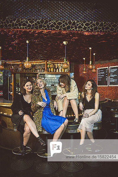 Vier glückliche Frauen sitzen in einem Club an der Bar
