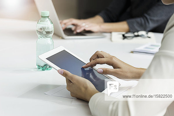 Nahaufnahme einer Geschäftsfrau mit Tablett während einer Besprechung im Büro