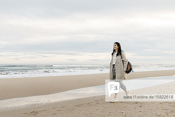 Junge Frau geht bei Sonnenuntergang an einem abgelegenen Strand spazieren