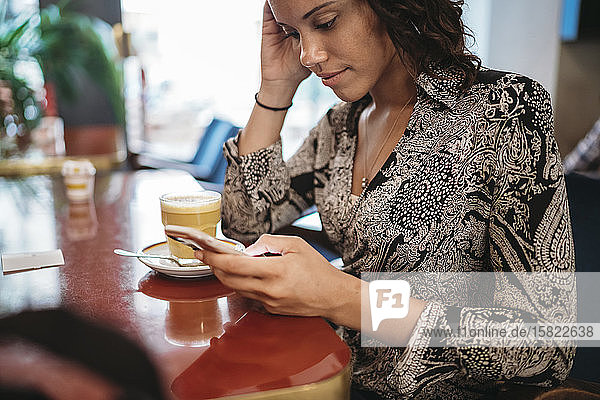 Nahaufnahme einer jungen Frau  die ein Smartphone in einem Cafe benutzt