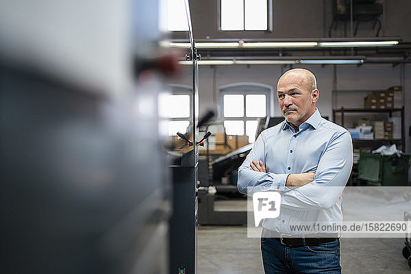 Geschäftsmann betrachtet eine Maschine in einer Fabrik