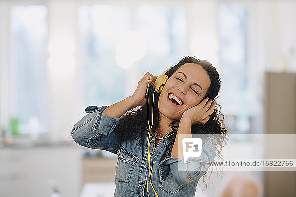 Glückliche Frau hört Musik  singt und tanzt  benutzt Smartphone und Kopfhörer