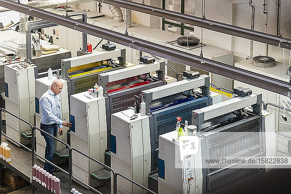 Businessman standing at machines in a printing plant