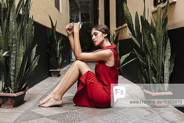 Porträt eines weiblichen Teenagers in rotem Trägerkleid vor einer Wand
