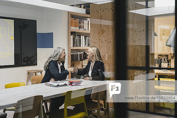 Happy mature and young businesswoman shaking hands in loft office