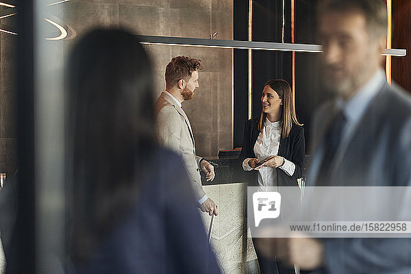 Business people talking at reception in hotel lobby