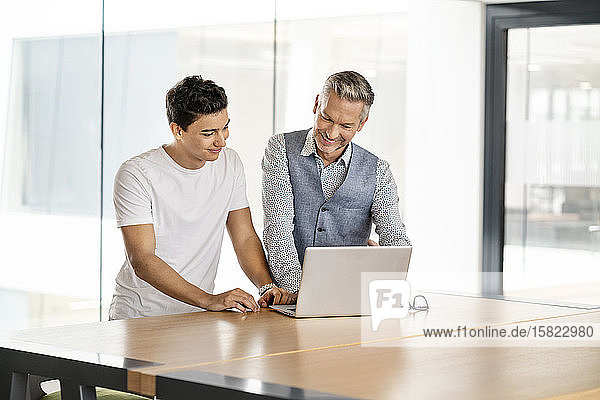 Senior businessman working with young colleague  using laptop