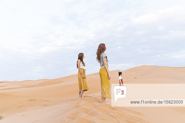 Three young women standing on sand dune in Sahara Desert  Merzouga  Morocco