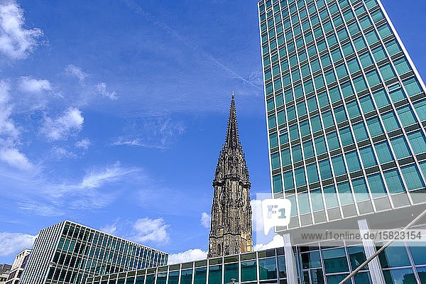 Deutschland  Hamburg  Niedrigwinkelansicht eines Bürohochhauses mit dem Turm der St.-Nikolaus-Kirche im Hintergrund