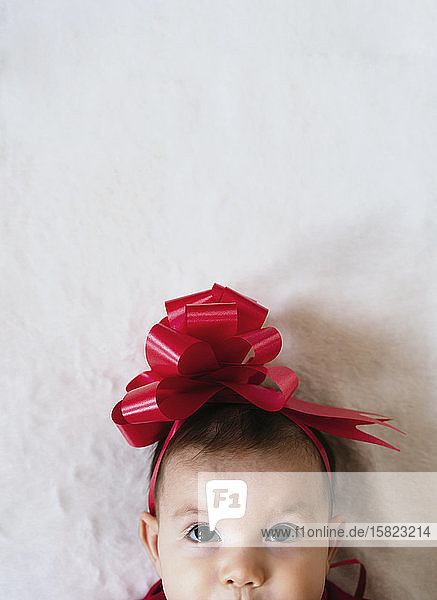 Porträt eines kleinen Mädchens mit roter Schleife auf dem Kopf  das nach oben schaut