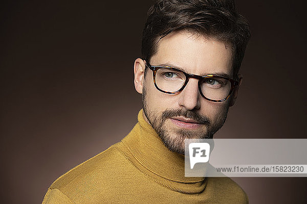 Porträt eines selbstbewussten Mannes mit Brille und gelbem Pullover