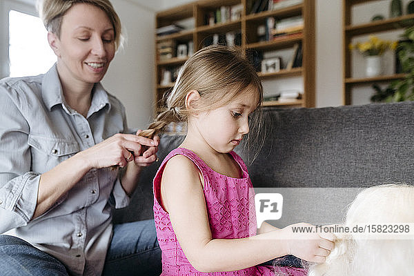 Mother braiding her daughter's hair on the couch