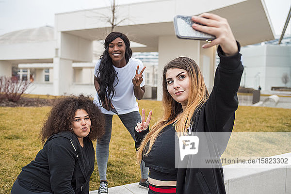 Three sportive young women taking selfie in the city