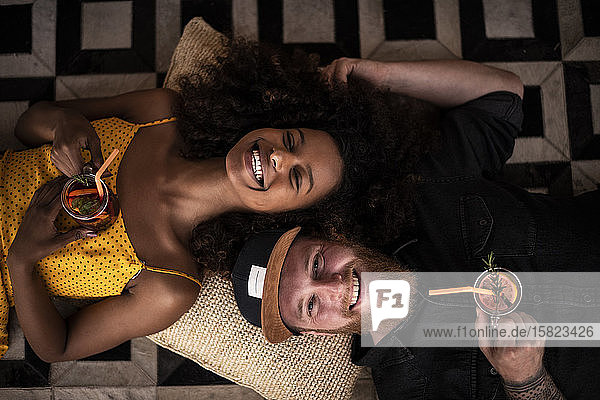 Porträt eines glücklichen Paares  das auf dem Boden liegt und frischen Eistee trinkt